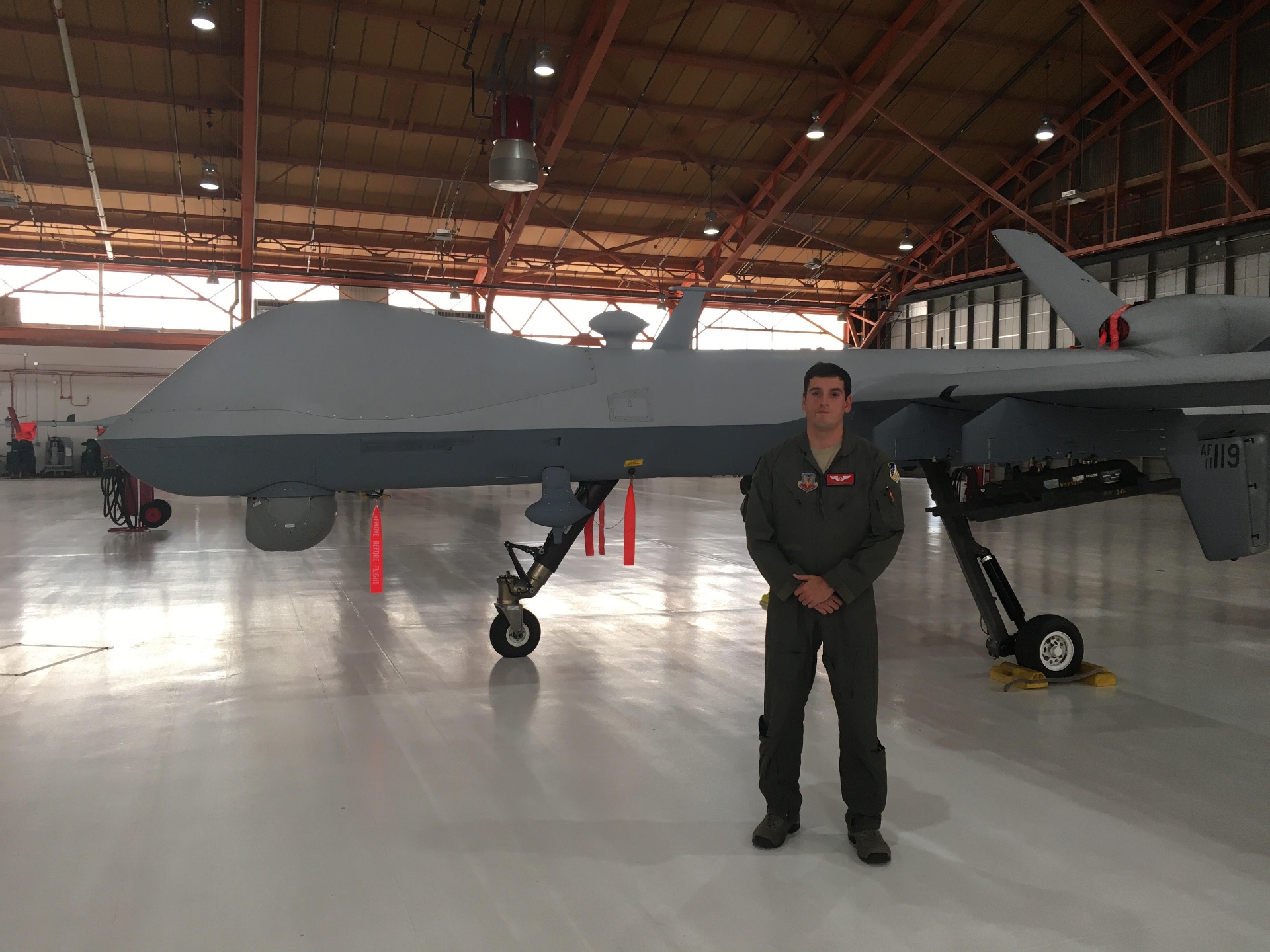 Tanner Yackley standing in front of an MQ-9 Reaper inside a hangar.